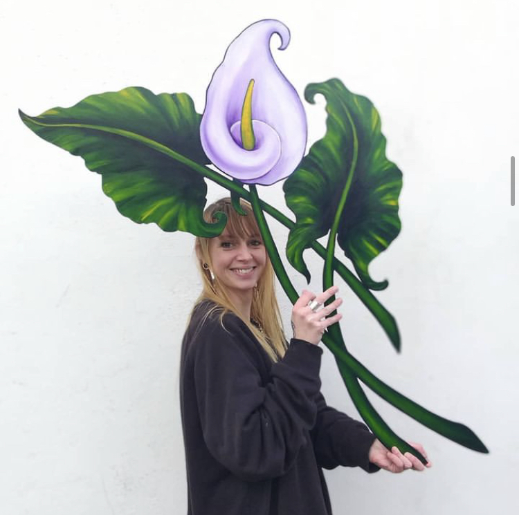 Hand painted wood cut out artwork by Lily Loy of a pale purple and green Cala lily. 